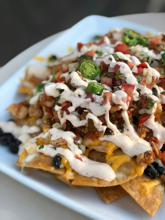 Nachos con queso fundido, guacamole y pulled pork