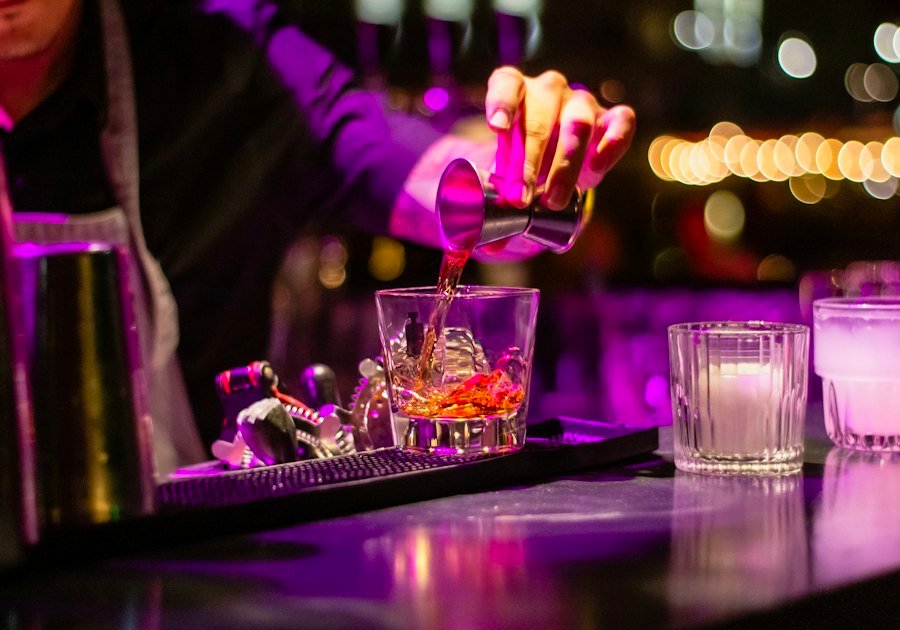 Bartender sirviendo un cocktail con luz violeta