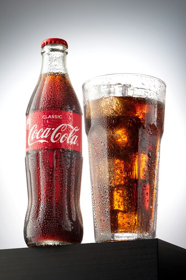 Botella de Coca-Cola y vaso con hielo